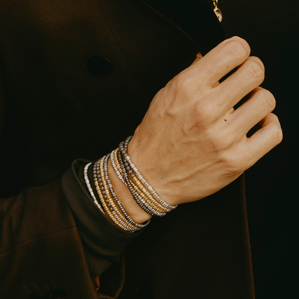 A bracelet with a combination of silver and grey titanium beads, featuring a half moon shape and a Tateossian gear tag.