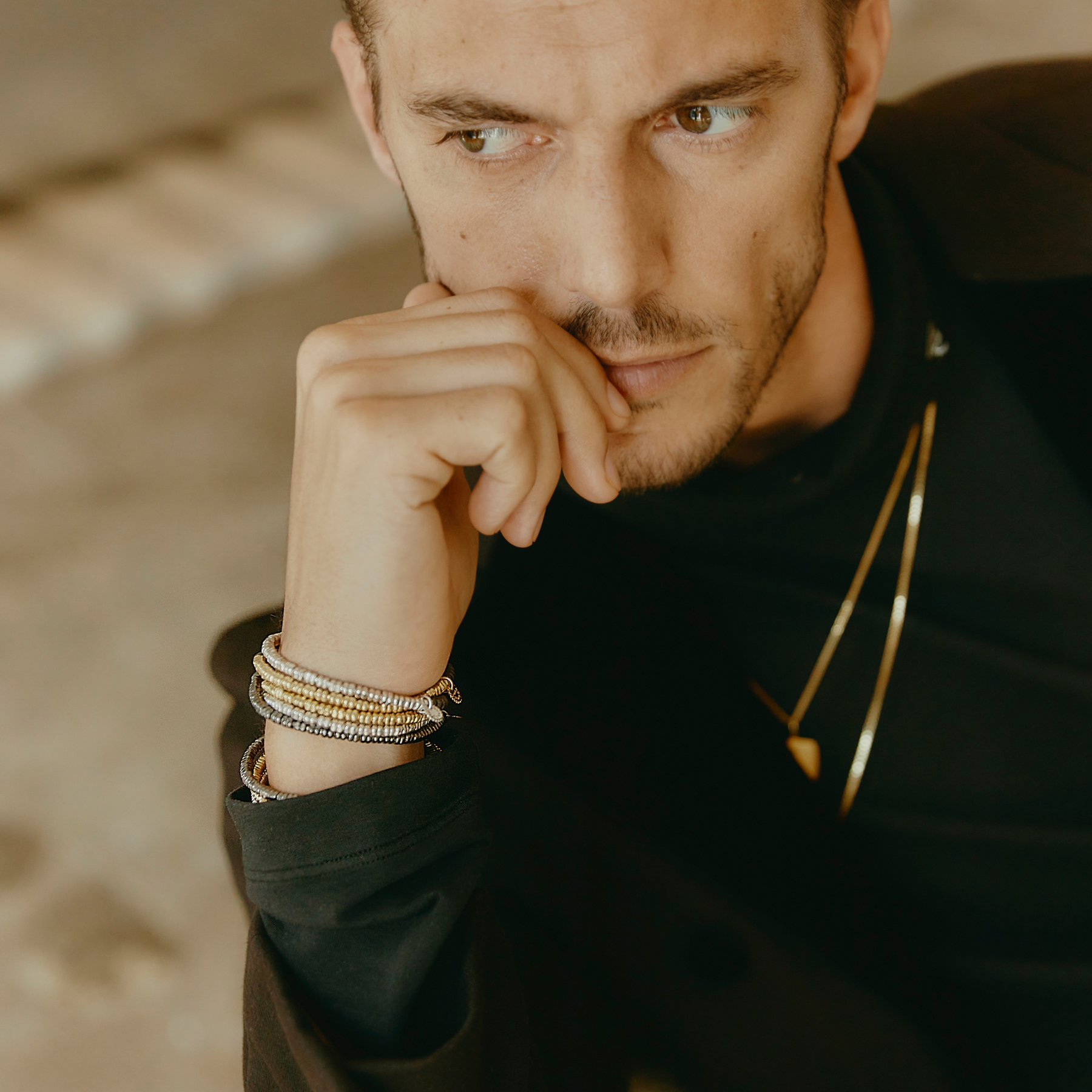 A bracelet with a combination of silver and grey titanium beads, featuring a half moon shape and a Tateossian gear tag.