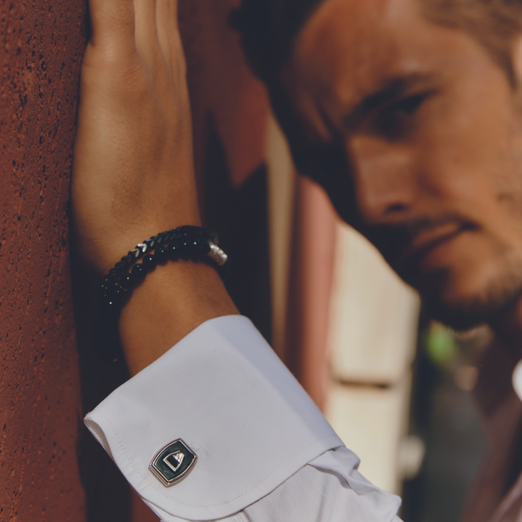 Chevron Click Bracelet In Matte Black worn on wrist of man dressed in white shirt, highlighting chevron chain and matte black clasp.