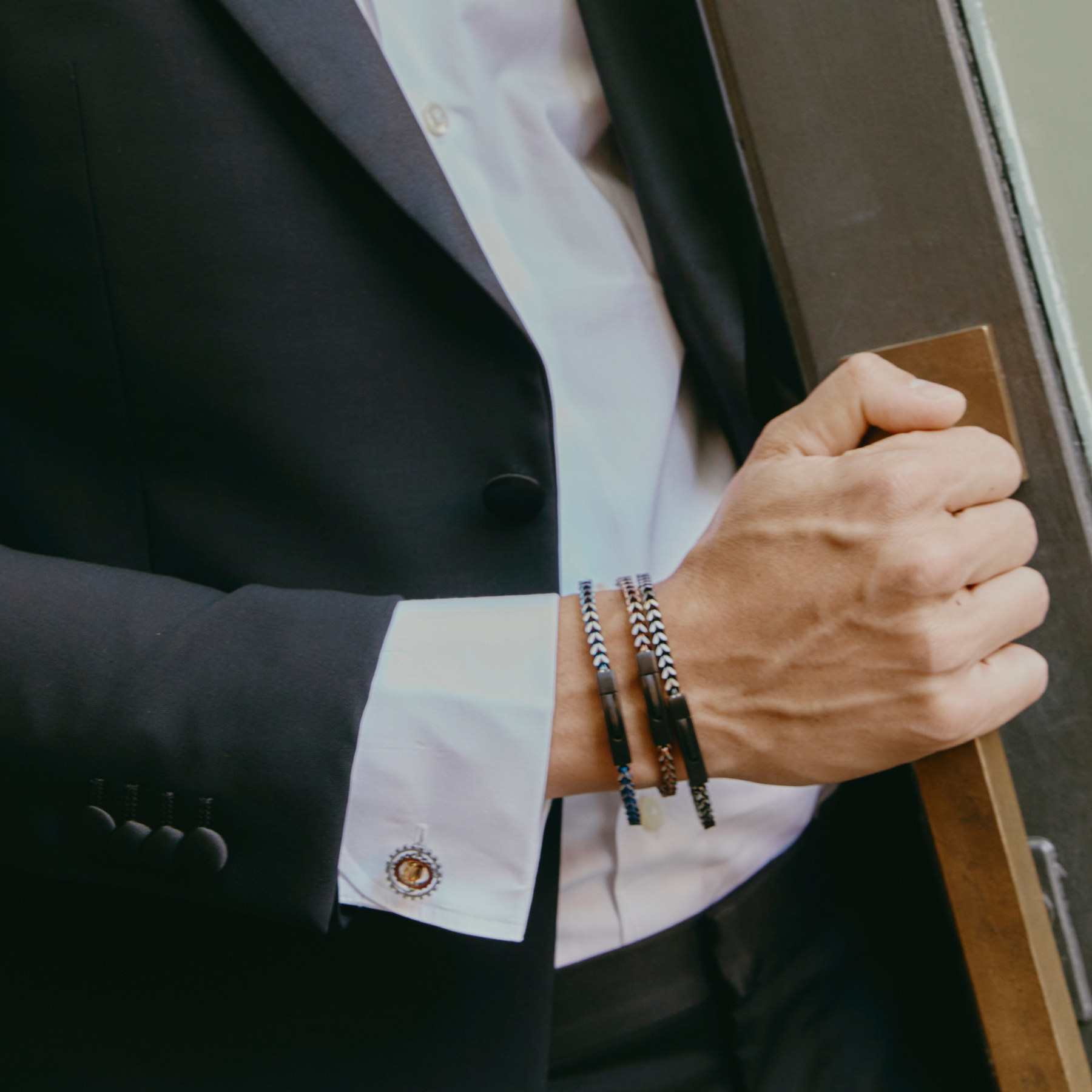 Man wearing Chevron Click Bracelet In Matte Black with chevron-patterned black chain and matte black clasp.
