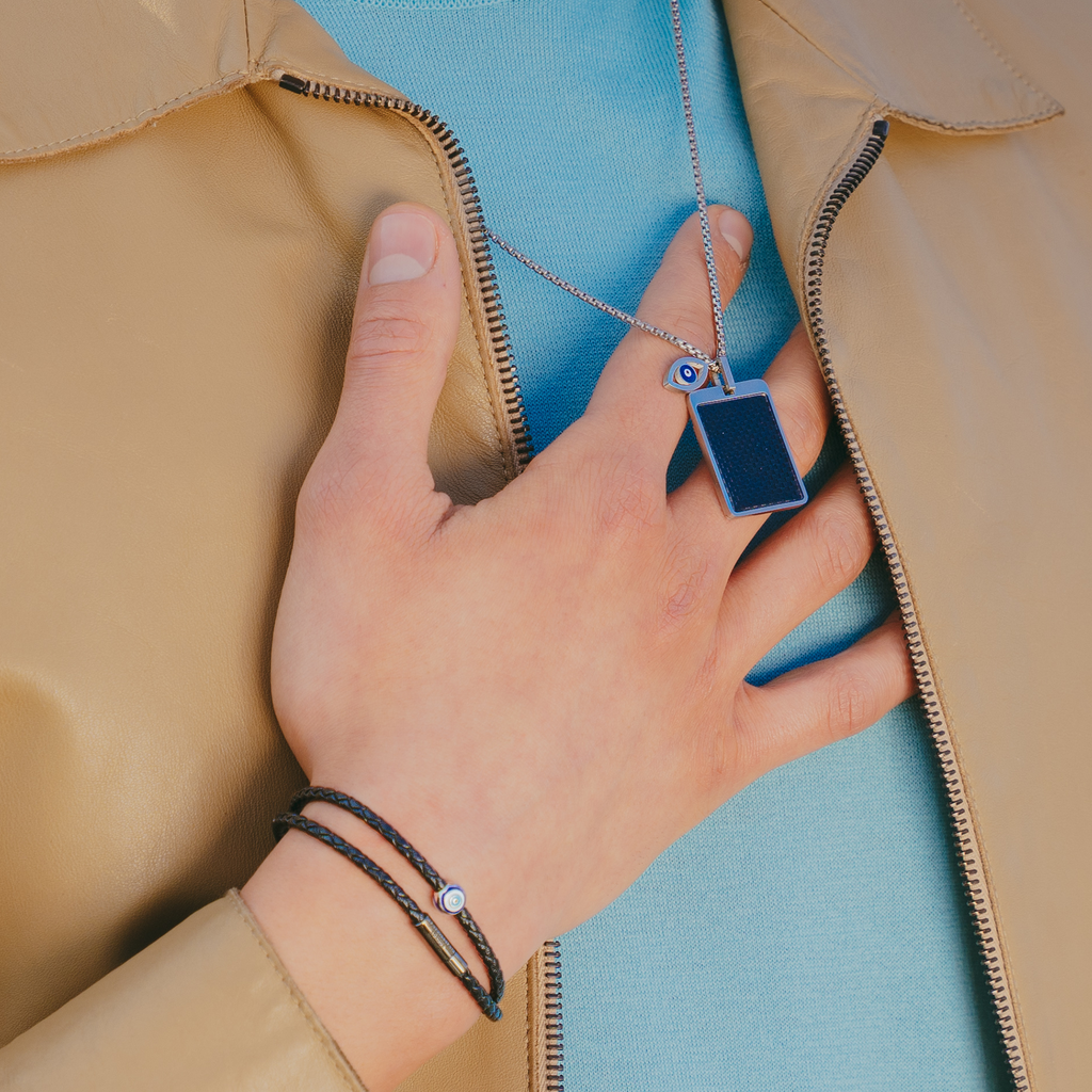 A black eco-friendly leather bracelet with a ruthenium-plated silver evil eye charm and a metal pop-clasp.