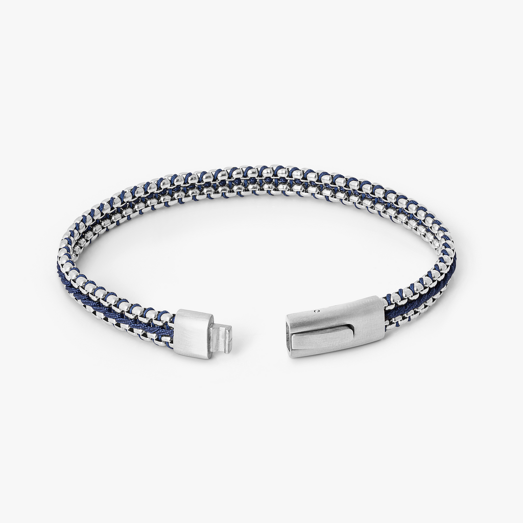 Tris Button bracelet in stainless steel with interlocking chain links, blue thread centre detail, and brushed button clasp.