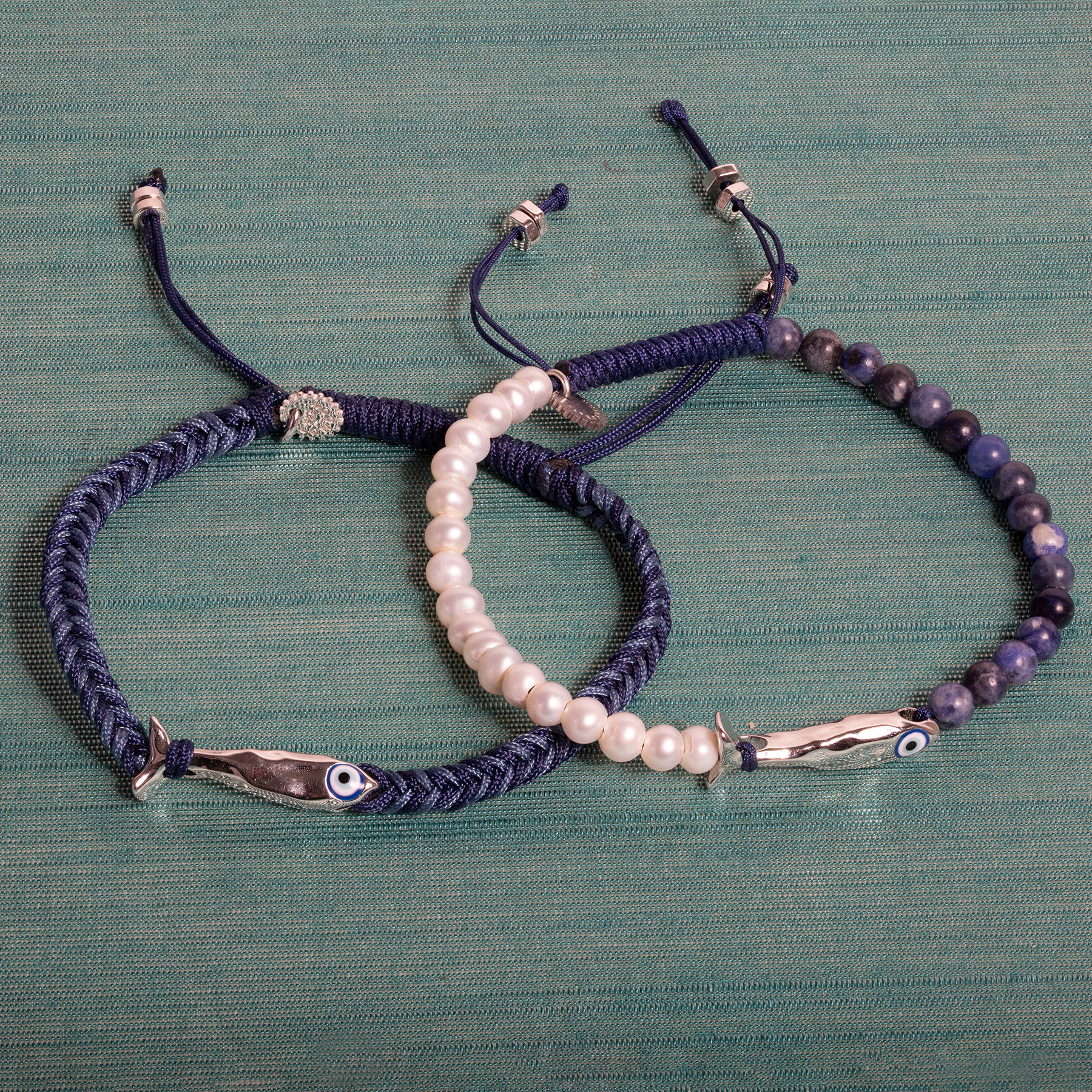Feng Shui fish macrame bracelet in blue with rhodium-plated sterling silver fish motif, blue enamel evil eye, and braided macramé band.