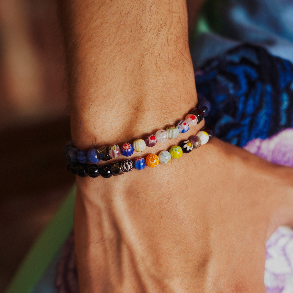 A multicolored beaded bracelet with blue sodalite and millefiori design, strung on an elastic band.
