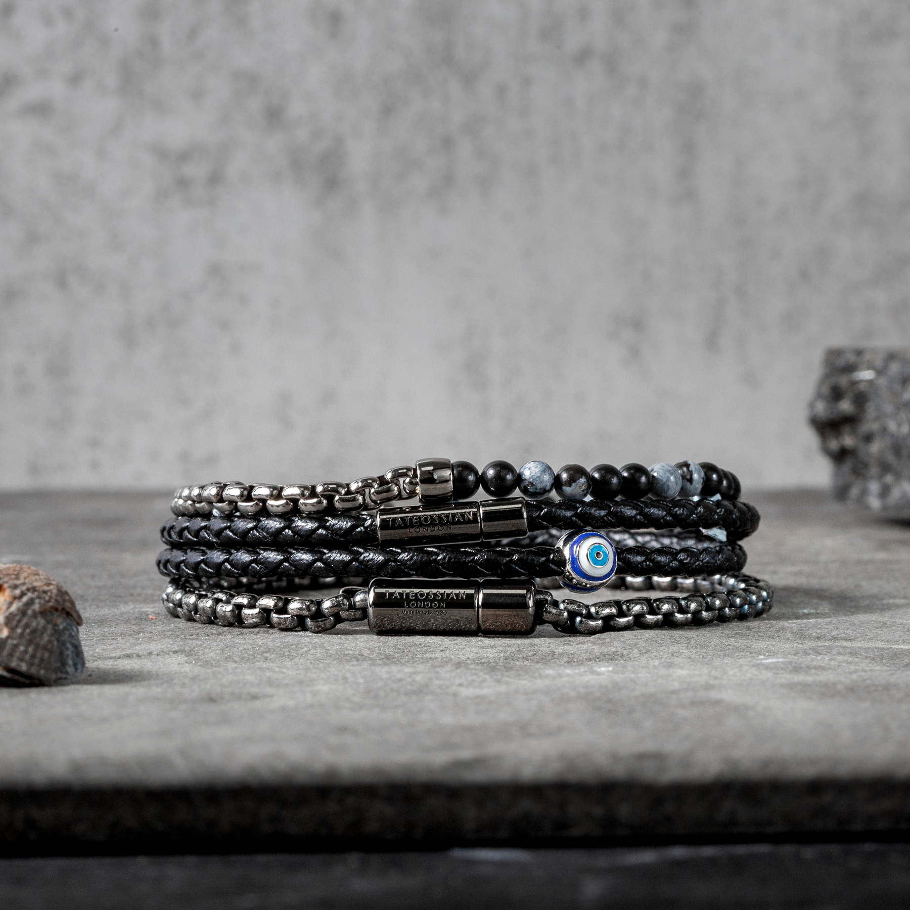 A black eco-friendly leather bracelet with a ruthenium-plated silver evil eye charm and a metal pop-clasp.