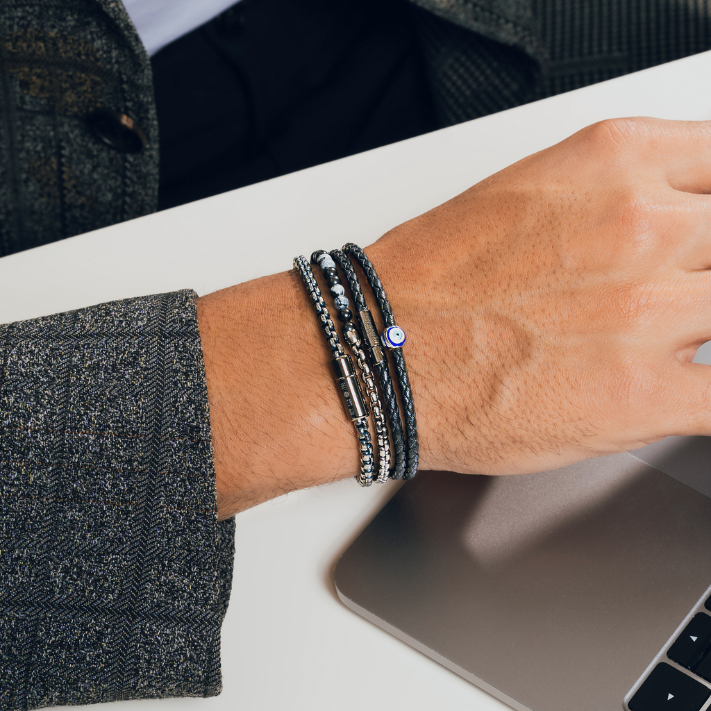 A black eco-friendly leather bracelet with a ruthenium-plated silver evil eye charm and a metal pop-clasp.