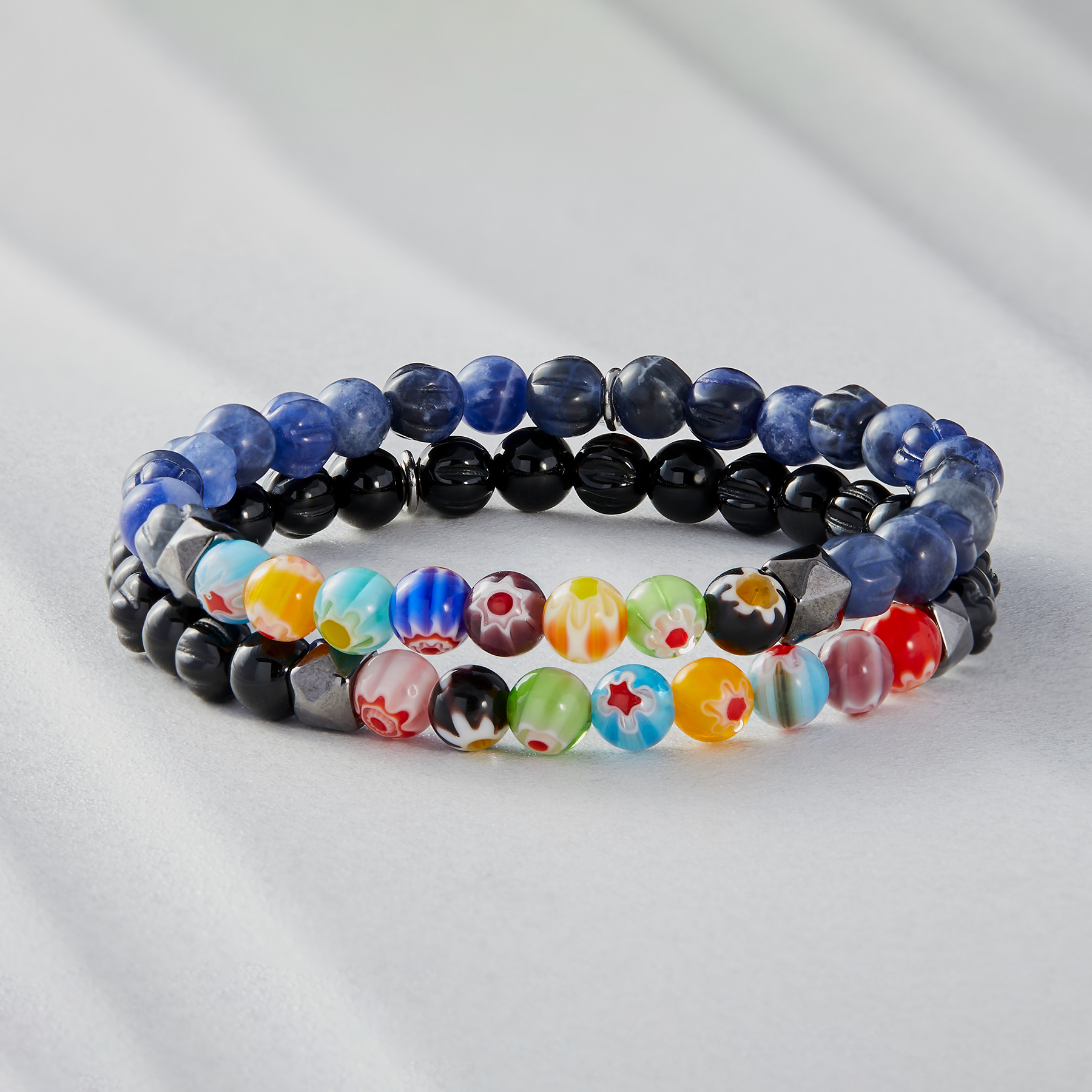 A multicolored beaded bracelet with blue sodalite and millefiori design, strung on an elastic band.