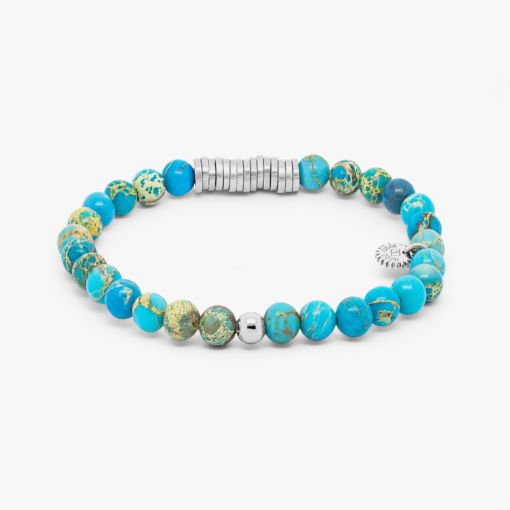 A bracelet with blue Impression Jasper beads and silver-colored discs, presented against a white background.