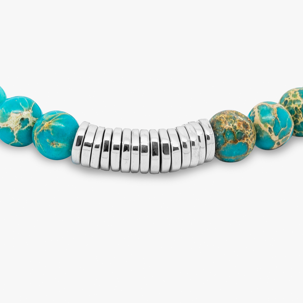 A bracelet with blue Impression Jasper beads and silver-colored discs, presented against a white background.