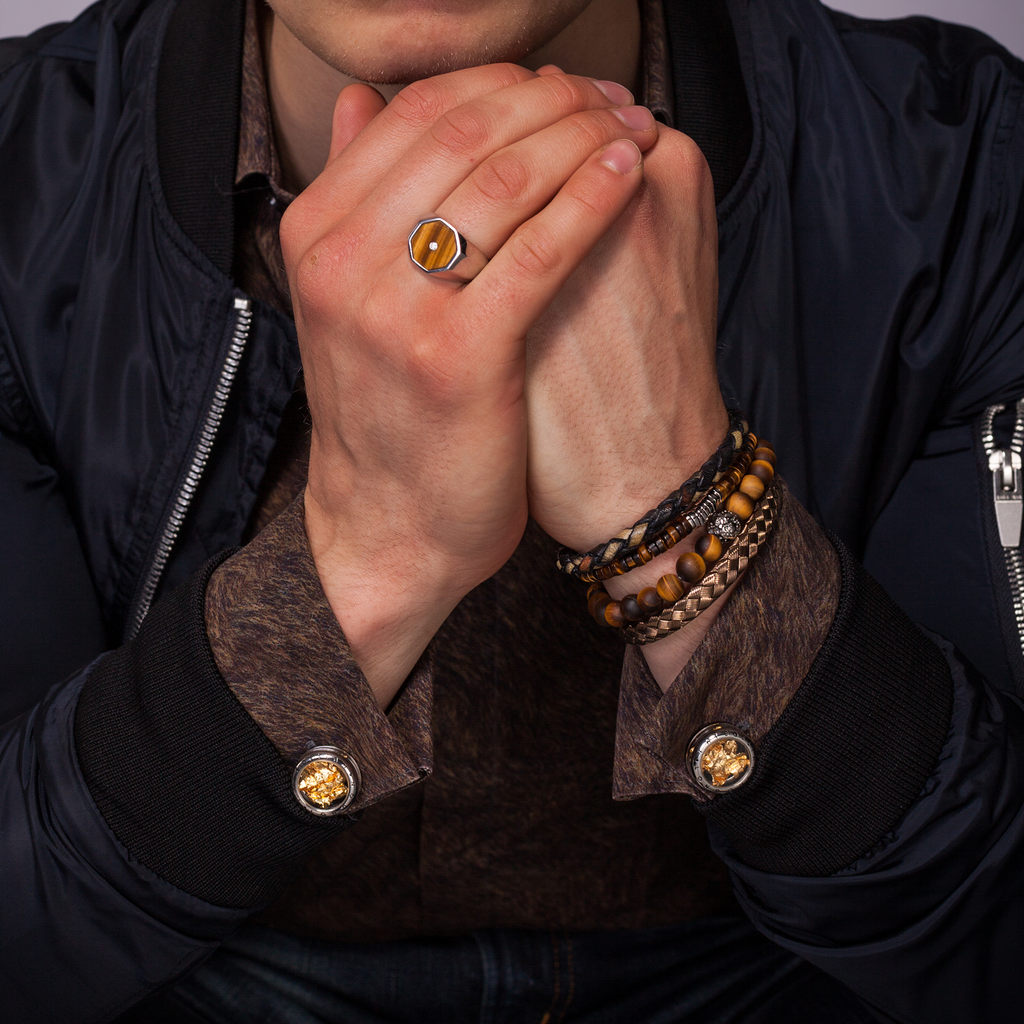 A pair of gunmetal finish cufflinks with black enamel detailing and gold leaf design.