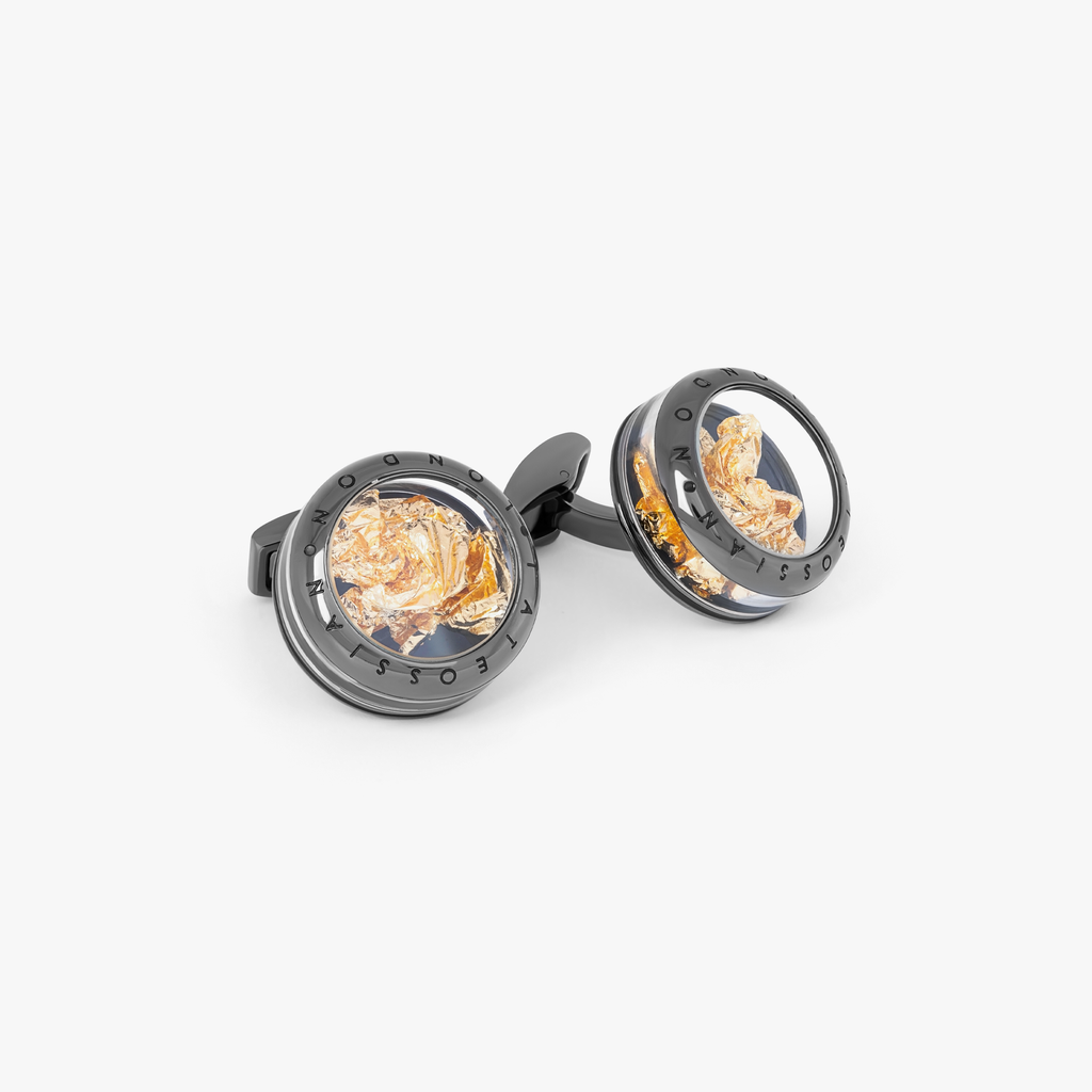 A pair of gunmetal finish cufflinks with black enamel detailing and gold leaf design.