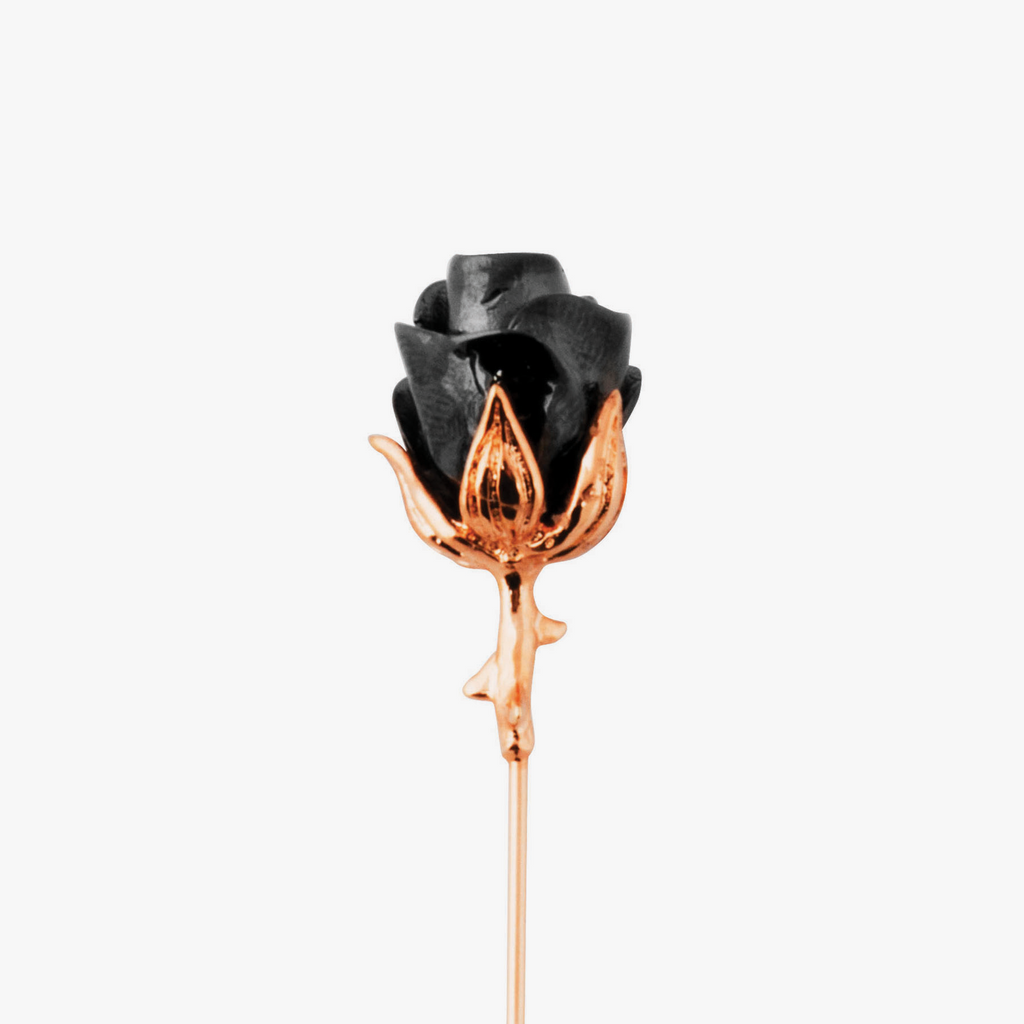 A rose-shaped lapel pin with a black enamel center, rose gold stem, and gunmetal accents.