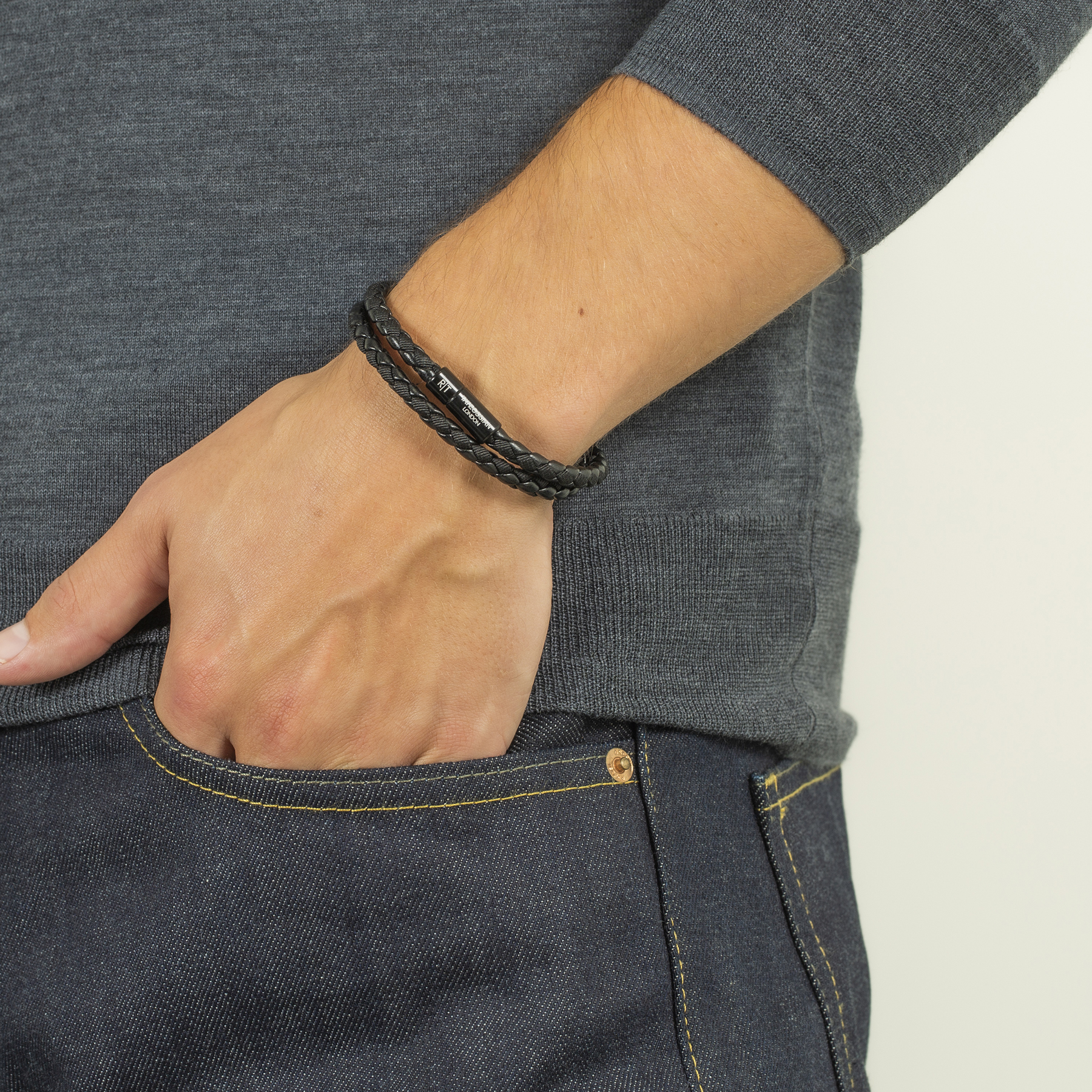 Close-up of a wrist wearing the Chelsea Leather Bracelet In Black With Aluminium Clasp with black braided fabric and leather.