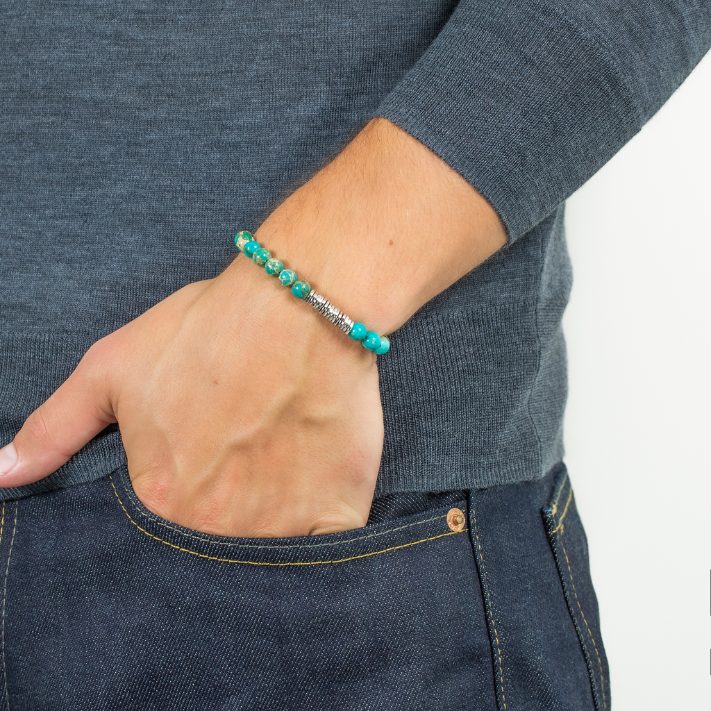 A bracelet with blue Impression Jasper beads and silver-colored discs, presented against a white background.