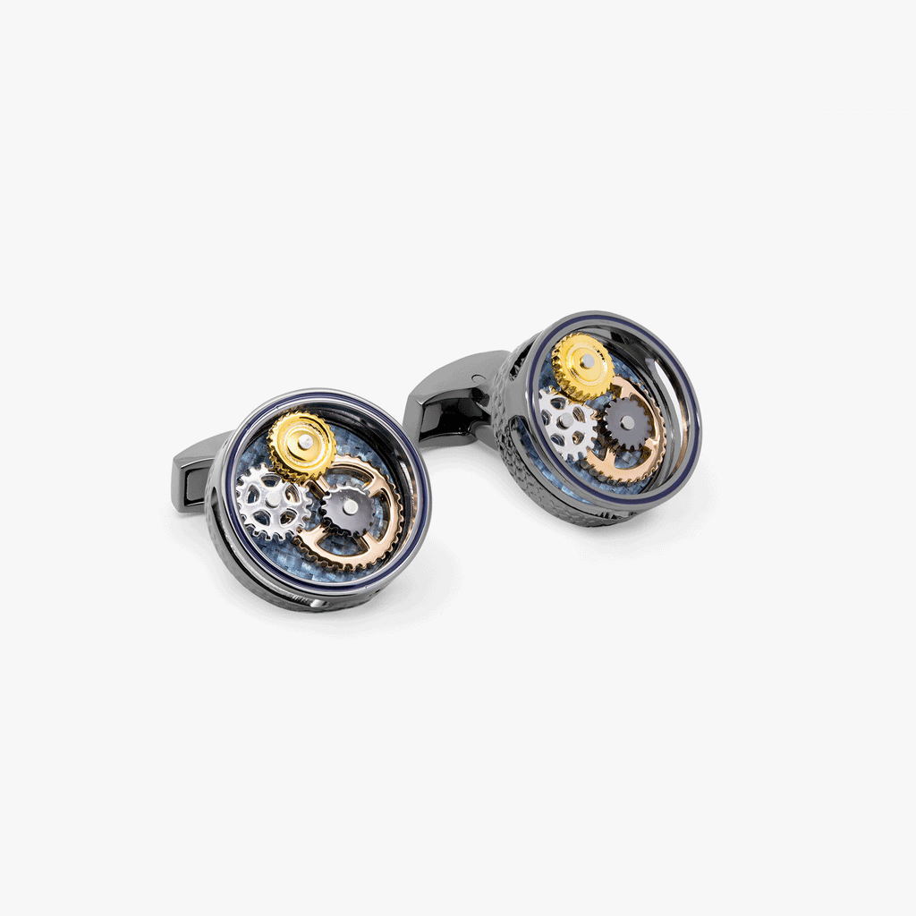A pair of round gear cufflinks with a gunmetal plated finish and visible mechanical gears within.