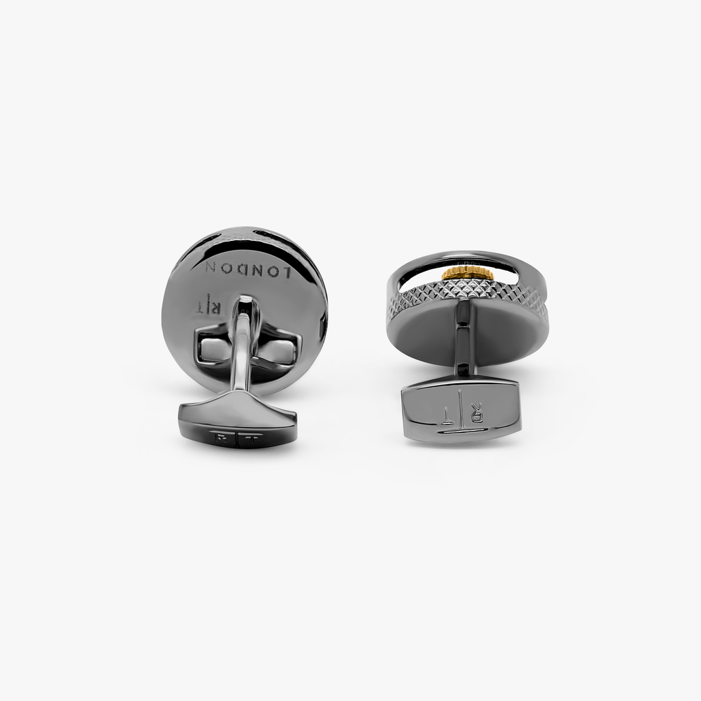 A pair of round gear cufflinks with a gunmetal plated finish and visible mechanical gears within.