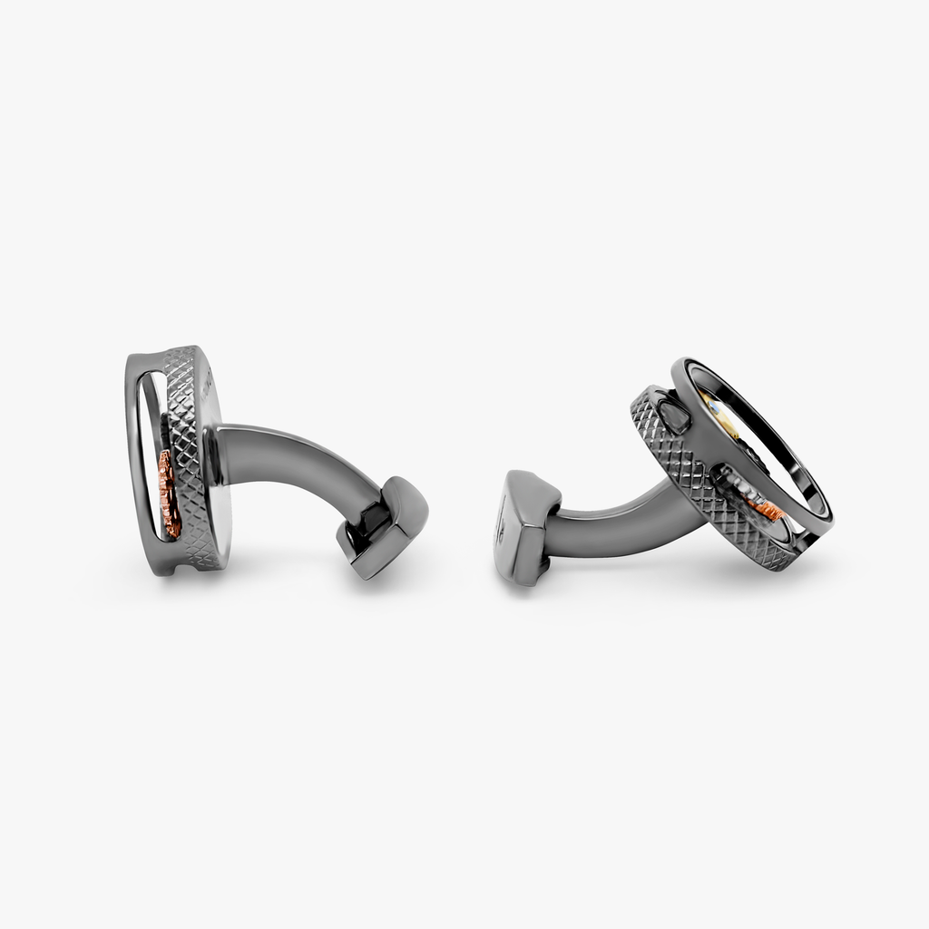 A pair of round gear cufflinks with a gunmetal plated finish and visible mechanical gears within.